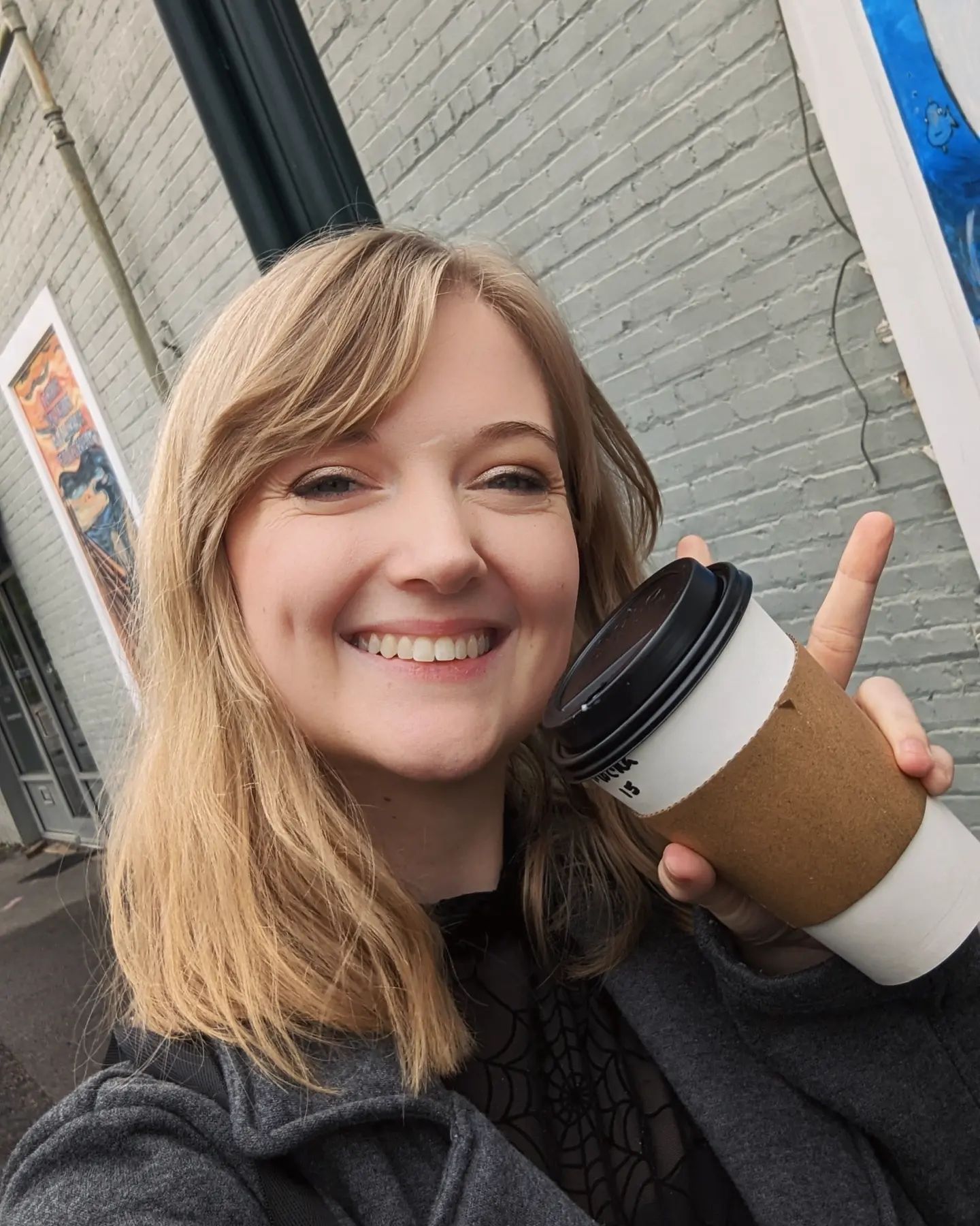 Brooklyn smiling while holding coffee.